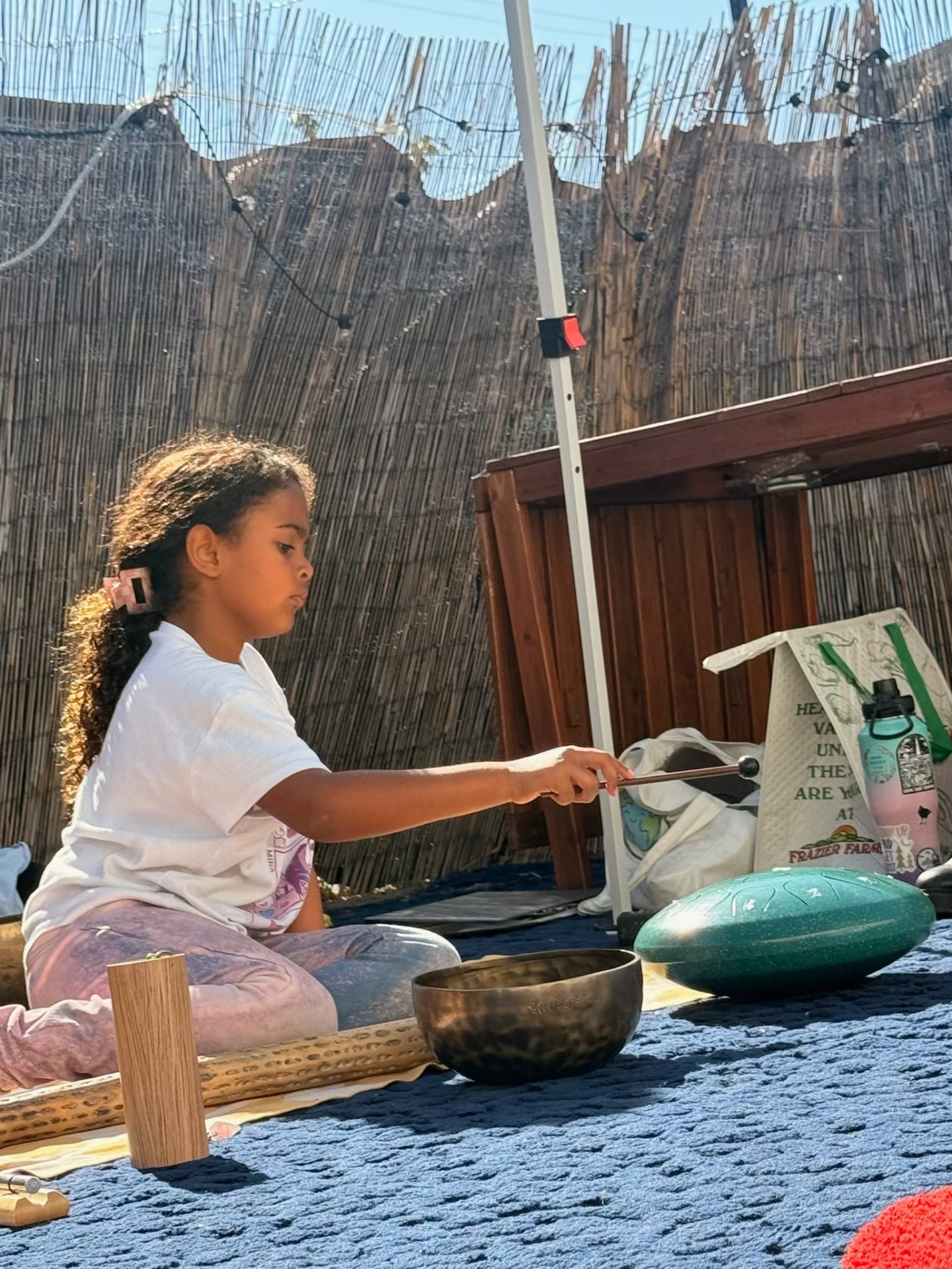 Eliana playing a singing bowl at a Clicking World pop-up